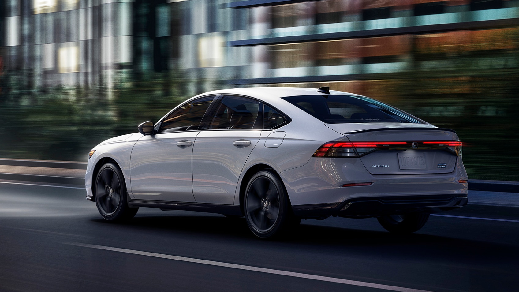 Rear side view of white Accord driving along a city street.