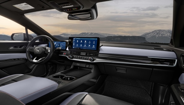 Plan large intérieur du volant, du tableau de bord et de la console avant. À travers le pare-brise, nous voyons des montagnes enneigées.