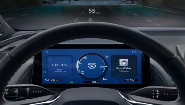 Gros plan de l’écran du bloc-instruments vu à travers le volant indiquant des renseignements comme l’heure, la température extérieure, la vitesse, le niveau de charge de la batterie et le compteur kilométrique.