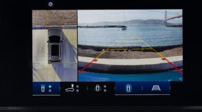 Closeup of touchscreen displaying a bird’s eye view of a Prologue in a parking spot and what the front cameras see: the curb in front, the ocean, and the Golden Gate Bridge.