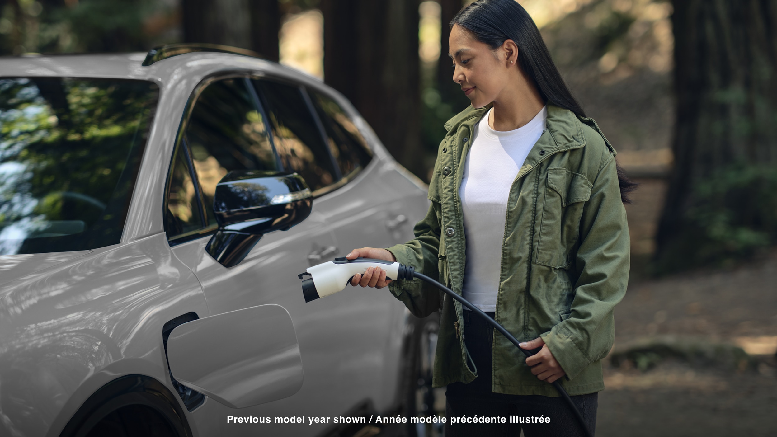 Plan d’une femme dans une forêt tempérée qui branche un câble de charge dans un Prologue blanc.
