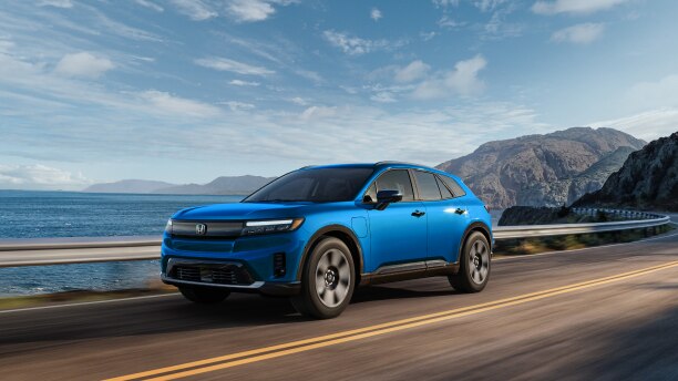 3/4 front side view of blue Prologue driving on coastal highway.