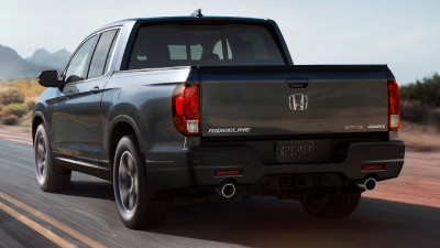 3/4 rear view of 2023 Ridgeline driving on desert highway, showcasing dual exhaust.