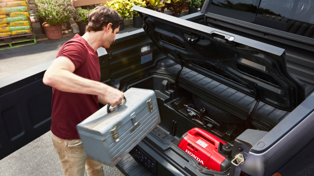 Man loading toolbox into lockable In-Bed Trunk.