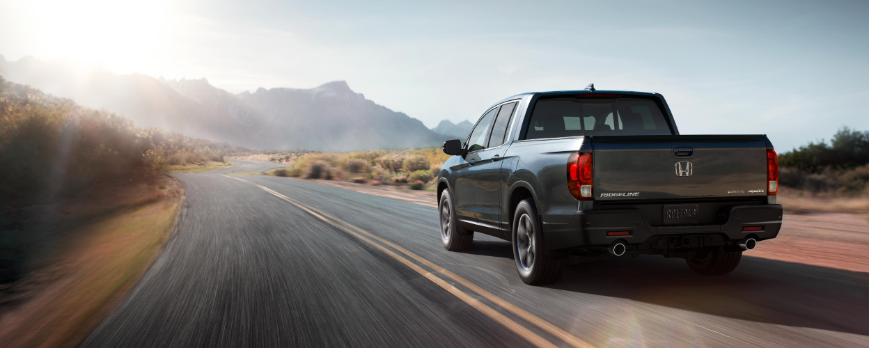 3/4 rear view of Honda Ridgeline driving on desert highway.