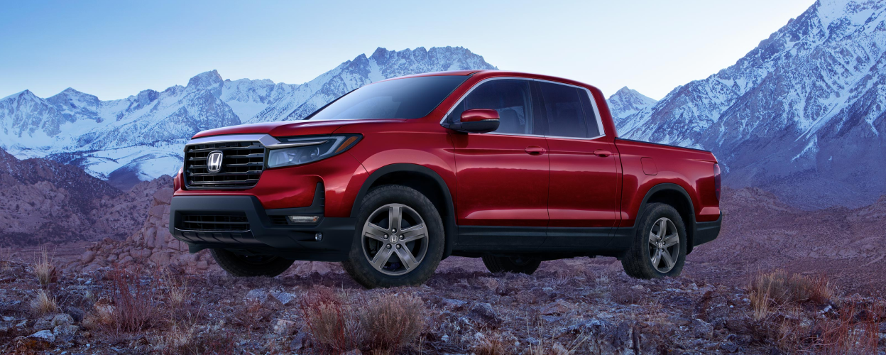 3/4 front view of red Honda Ridgeline parked amid barren tundra.