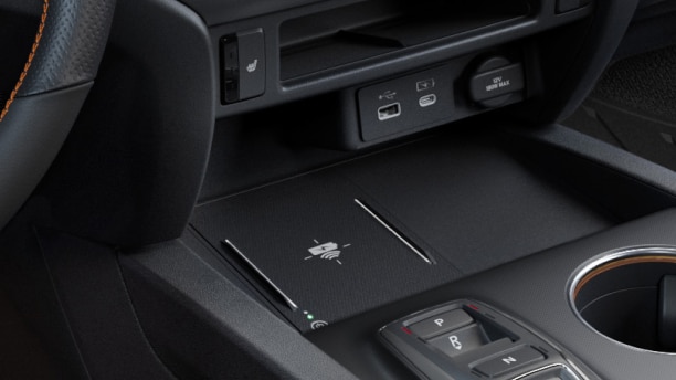 Closeup of USB charging ports and wireless charging pad in centre console.