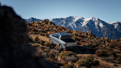 3/4 wide view of grey Ridgeline driving uphill in tundra.