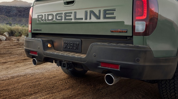 3/4 rear view of grey Ridgeline on a dirt road showcasing dual exhaust.