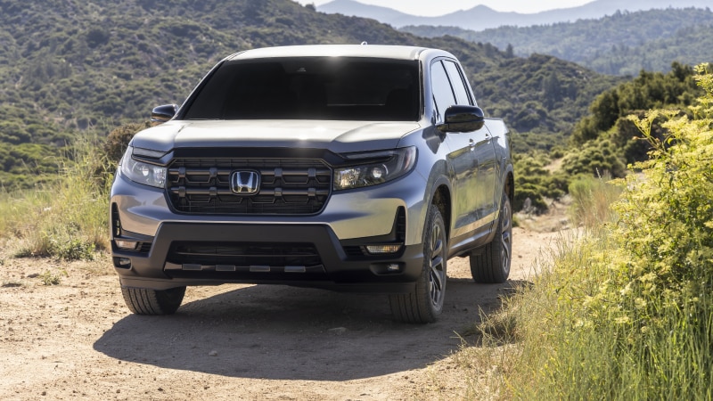 3/4 wide view of grey Ridgeline driving uphill.