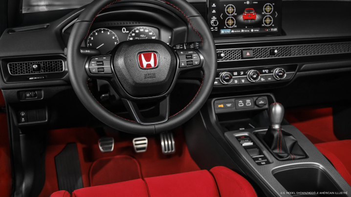 Medium interior closeup of steering wheel, dashboard, centre console, and gear shifter. 
