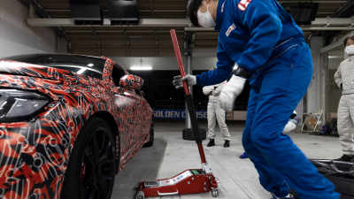 A Type R, with a funky red paint job with white Type R monograms, in a garage about to get lifted with a jack.