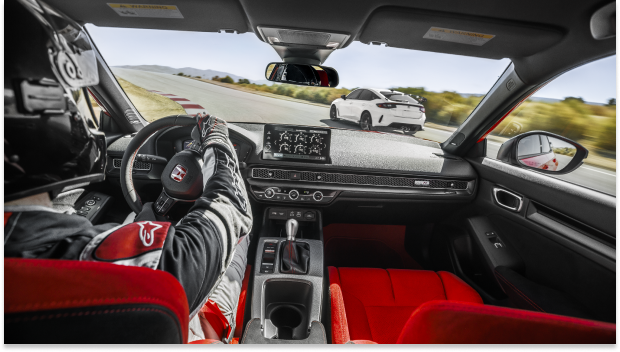 Interior shot, over pilot’s shoulder, showcasing the Type R’s cockpit as it races on a track.