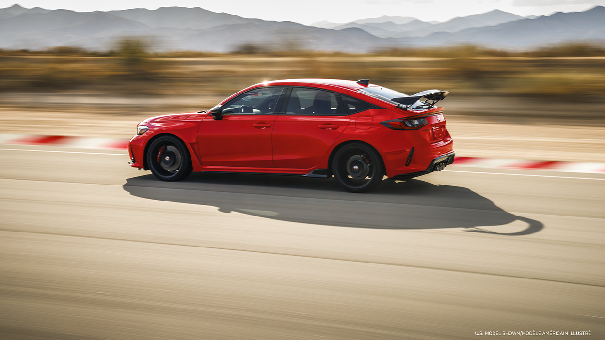 Sideview of red Type R racing on a track.