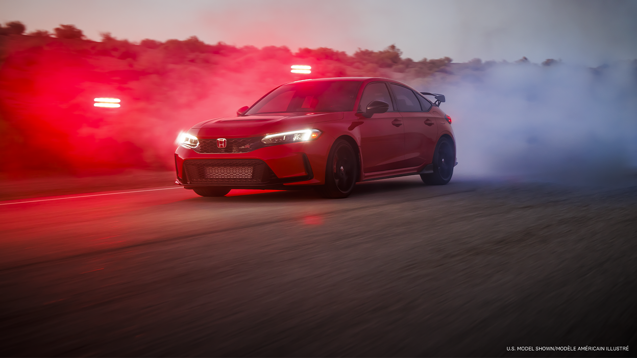 3/4 front view of a red Type R burning rubber on a desert road at dusk. 