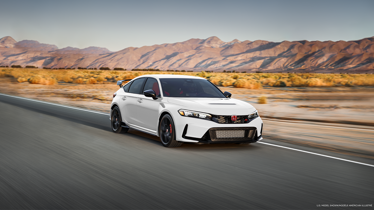3/4 front view of white Type R driving on straight desert highway.