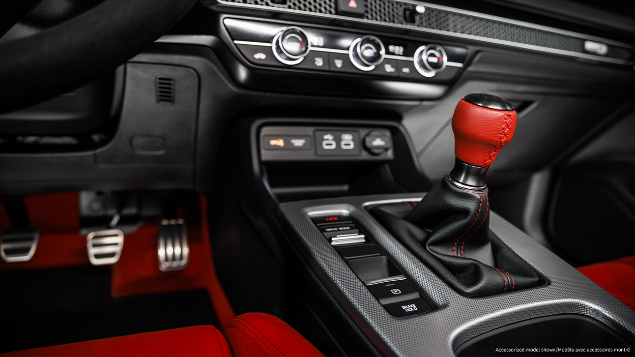 Closeup of shifter with red leather handle and centre console.