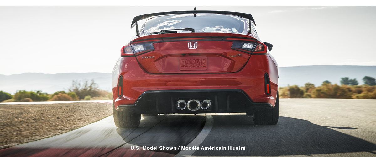 Straight on closeup of the triple centre exhaust on a red Type R racing on a track.