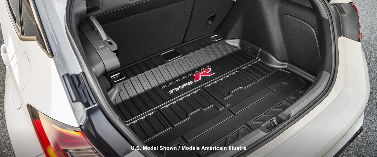 Closeup of an open trunk on a white Type R, showing the speakers and the custom-fit “Type R” branded rubber trunk mat. 