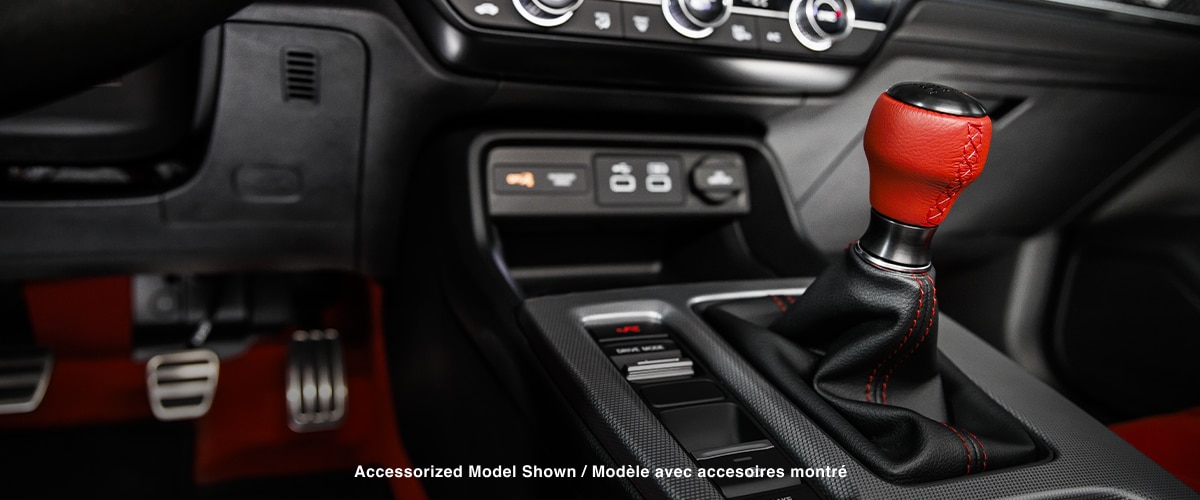 Closeup of shifter with red leather handle and centre console.