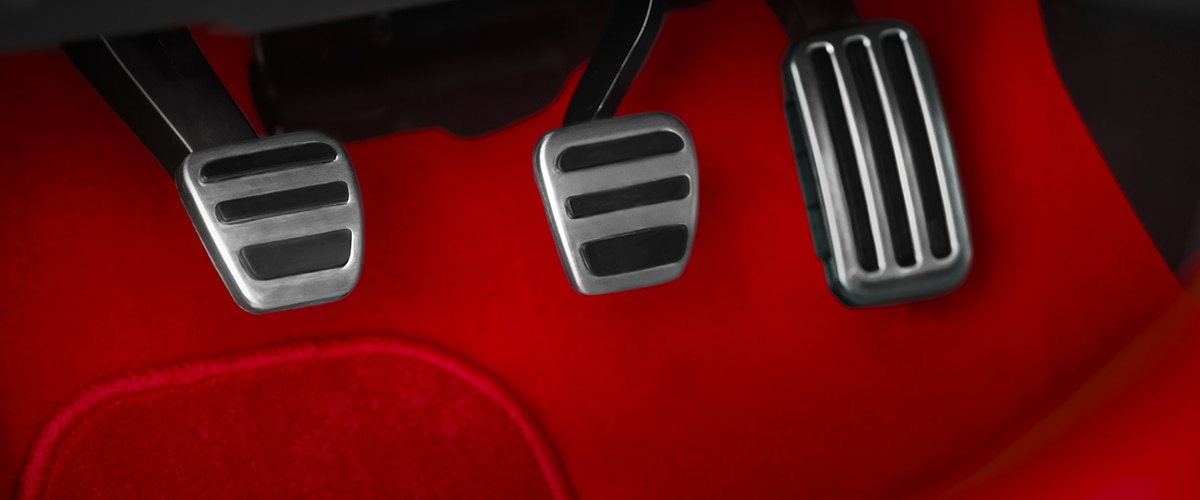 Closeup of aluminum-trimmed sport pedals and red felt footwell.