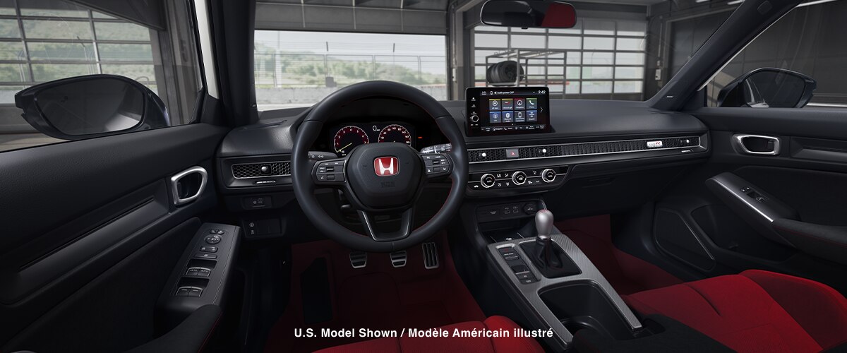 Panoramic view of steering wheel and front dashboard. Out the windshield, we see an open racing garage door. 