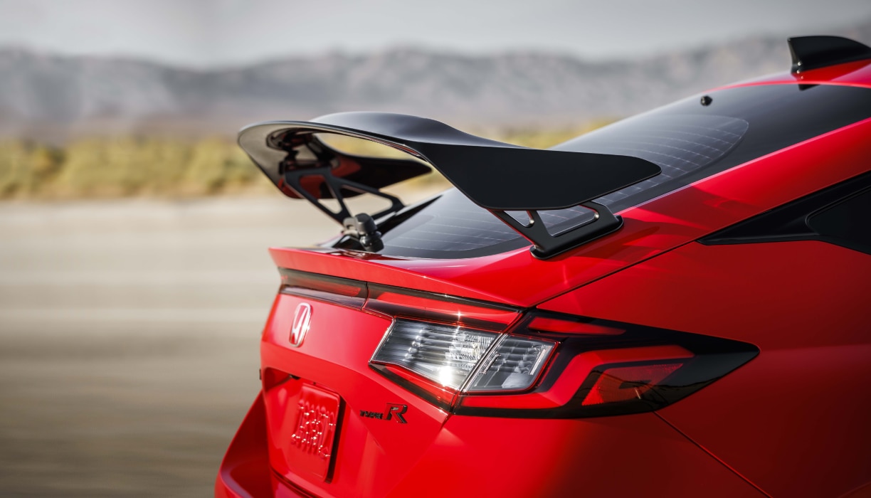 ¾ image of red Type R rear spoiler in an outdoor space,