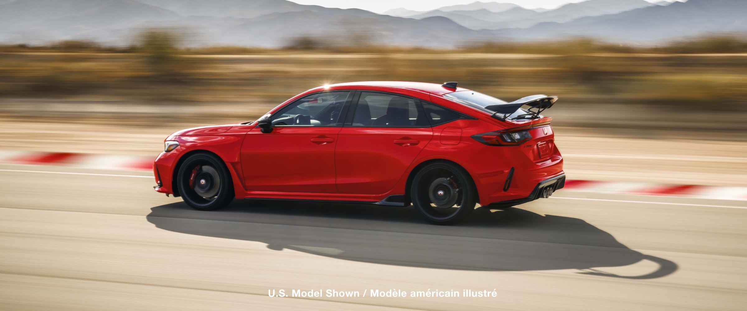Sideview of red Type R racing on a track.