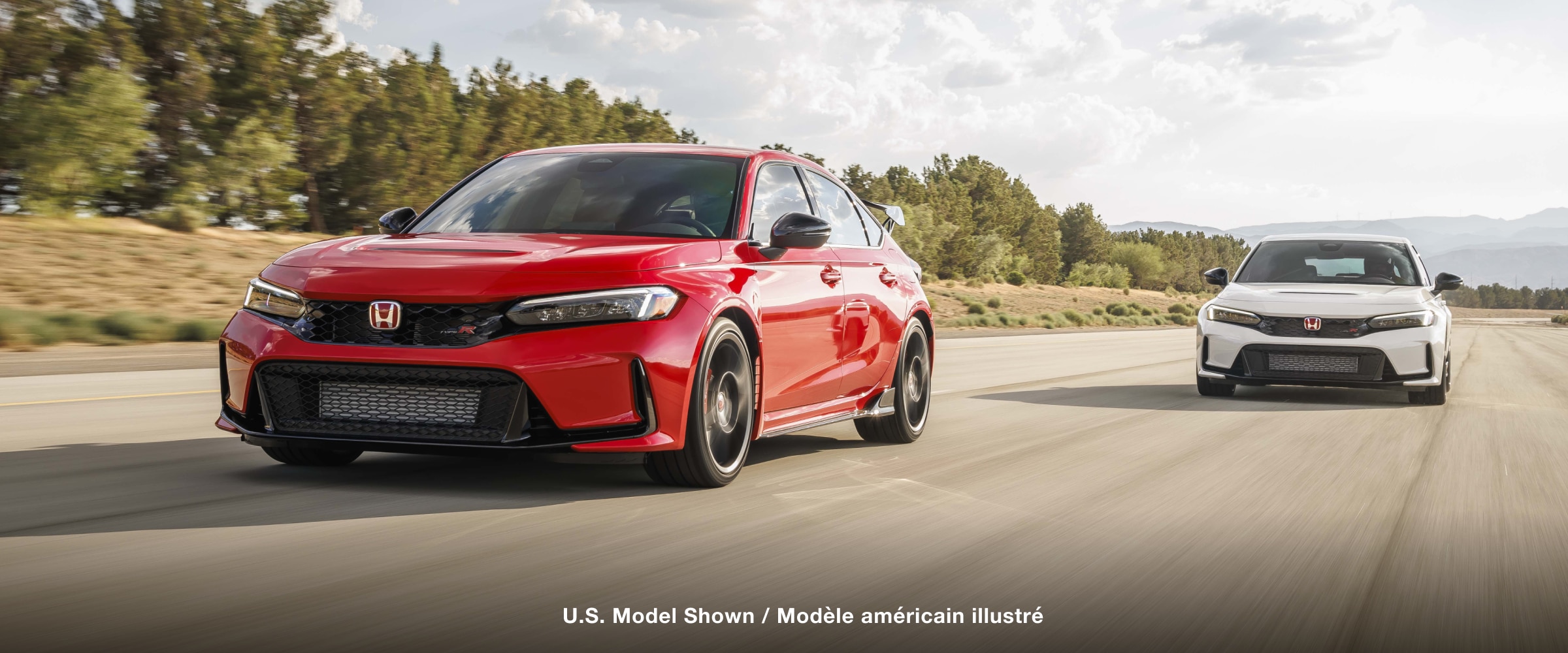 3/4 front view of a red Type R and a white Type R racing toward camera in a closed track circuit.