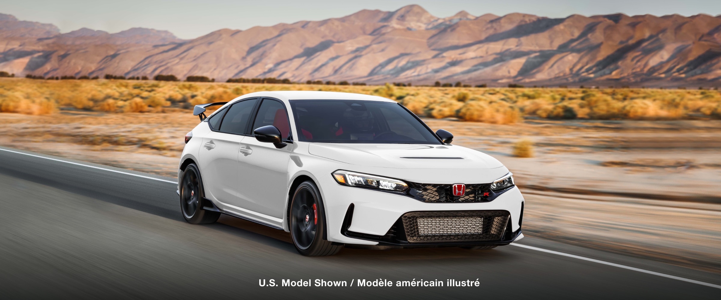 3/4 front view of white Type R driving on straight desert highway.