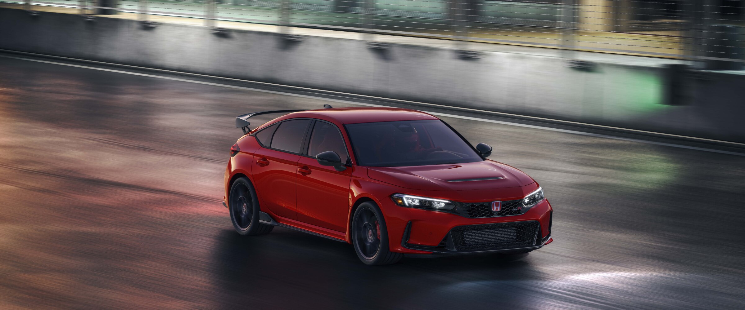 Vue aérienne de trois quarts d’une Type R rouge conduite sur un circuit de course la nuit.