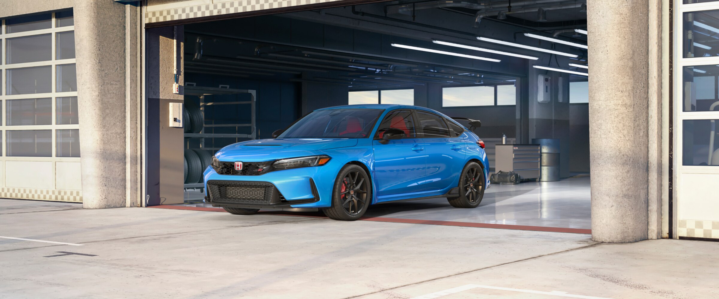 Vue avant d’une Type R bleu stationnée dans un garage d’écurie de course.