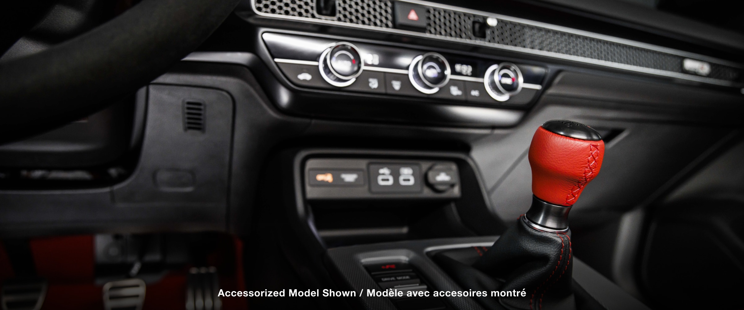 Closeup of shifter with red leather handle and centre console.