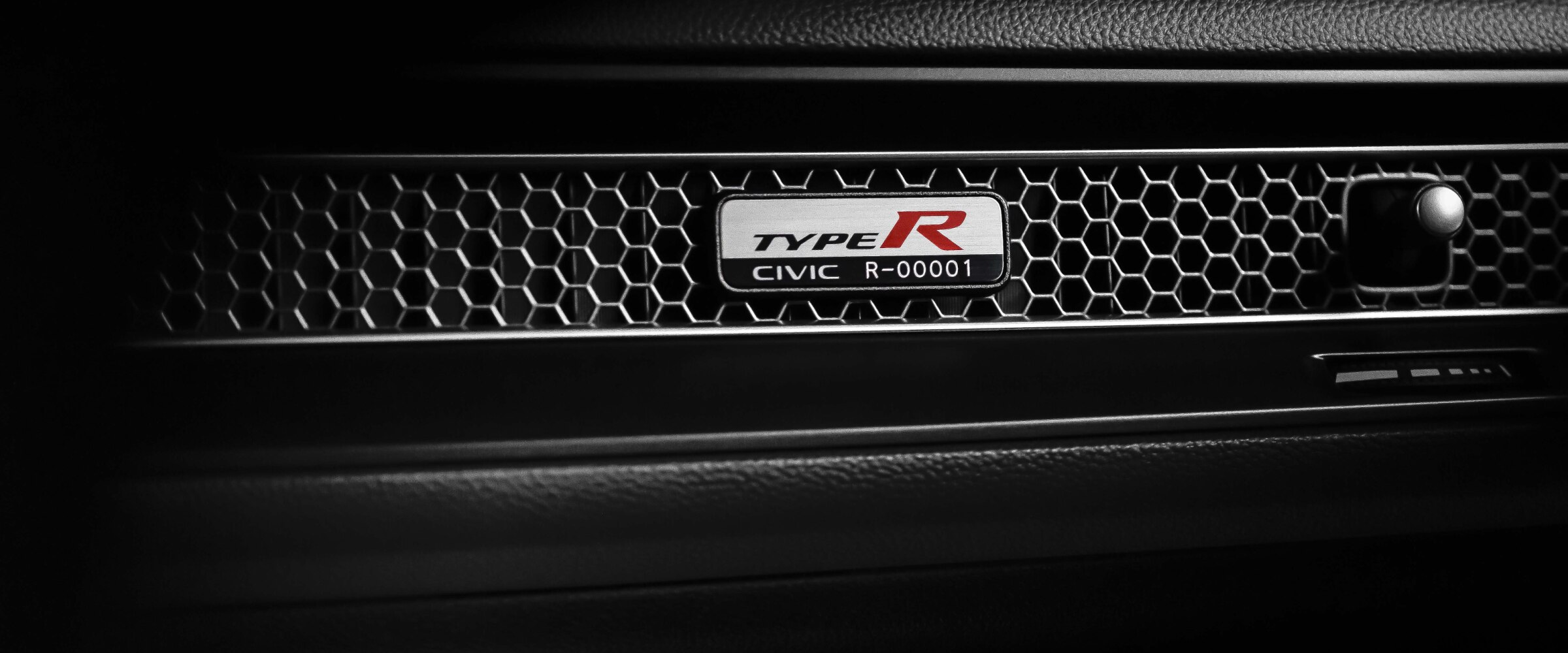 Gros plan de la plaque de numéro de série d’une Type R sur la bouche d’air alvéolée, sur le tableau de bord côté passager.