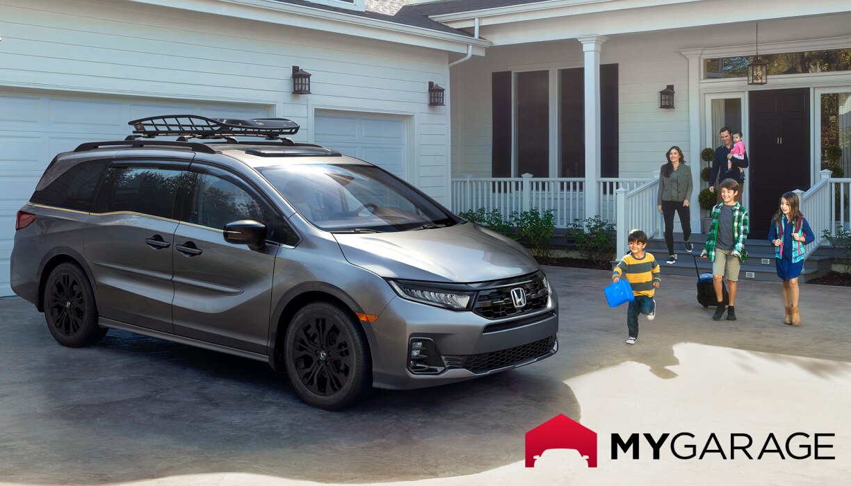 A grey Honda HR-V is parked in front of a white garage. Two adults and four children walk toward it, with one adult carrying a small child. 