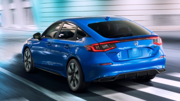 Plan rapproché de trois quarts d’une Civic à hayon bleue sur une rue urbaine bien éclairée la nuit.