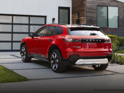 3/4 rear view of red Prologue parked in the driveway of a modern home.