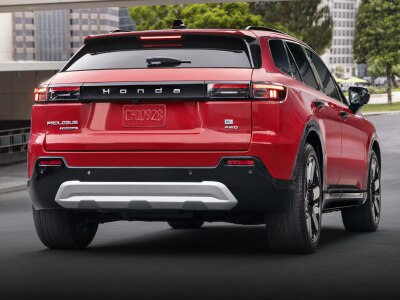3/4 rear view of a red Prologue driving on a quiet urban street.