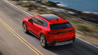Bird’s eye 3/4 rear view of red Prologue driving on coastal highway.