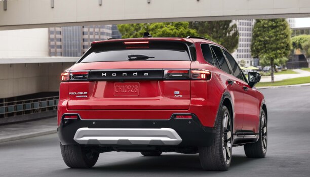 3/4 rear view of a red Prologue driving on a quiet urban street.