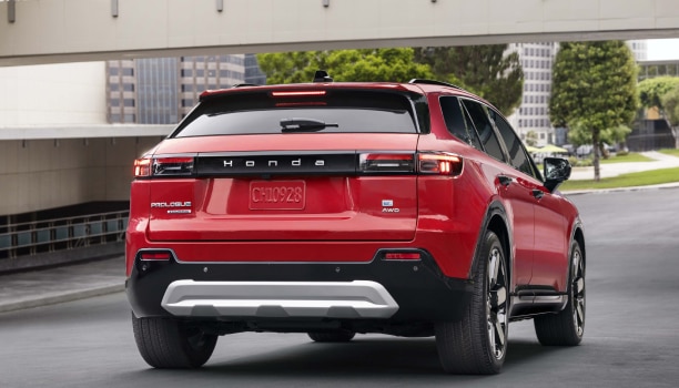 3/4 rear view of a red Prologue driving on a quiet urban street.