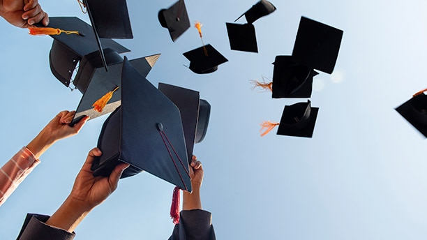 New graduates throwing their graduation hats into the air./ De nouveaux diplômés lancent leur chapeau de graduation en l'air