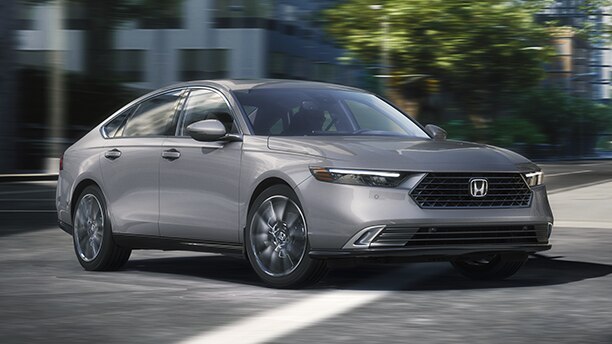 Plan de trois quarts avant d’une Accord grise négociant un virage dans une rue urbaine.
