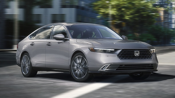 3/4 front view of grey Accord making a turn on a city street.