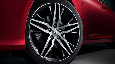Close-up view of a rear wheel and rims on a red Honda. 