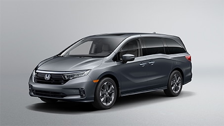 Side-view of a parked silver Honda van on a plain white backdrop.