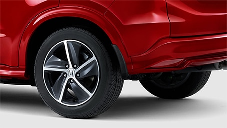 Cropped side-view of the rear half of a red Honda set against a white background.  	Vue latérale recadrée de la moitié arrière d'une Honda rouge sur un fond blanc.
