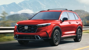 CR-V rouge circulant sur une route au milieu d’une forêt. 