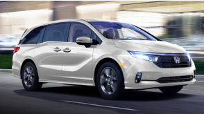 Plan de trois quarts latéral avant d’une Odyssey blanche sur une route urbaine, la nuit.