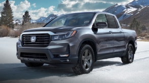 Vue de trois quarts de l’avant d’un Ridgeline gris dans un paysage enneigé.  